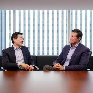 Two male American Securities employees in work attire chatting in an office