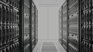 A symmetrical view looks down a brightly lit aisle flanked by tall rows of modern server racks, representing IT services sector.